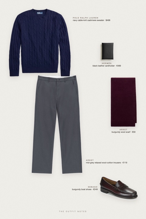 Flat-lay of the pieces in this outfit: navy cable-knit cashmere sweater, mid-grey relaxed wool-cotton trousers, burgundy boat shoes, burgundy wool scarf, black leather cardholder.