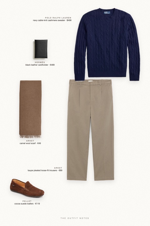 Flat-lay of the pieces in this outfit: navy cable-knit cashmere sweater, taupe pleated loose-fit trousers, cocoa suede loafers, black leather cardholder, camel wool scarf.