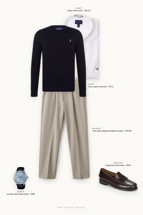 Flat-lay of the pieces in this outfit: navy cable crewneck, white oxford shirt, mink-grey pleated straight trousers, burgundy boat shoes, ice-blue dial dress watch.