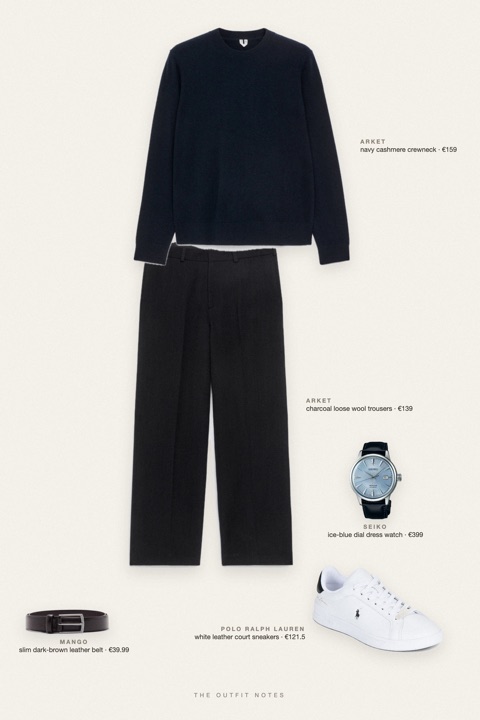 Flat-lay of the pieces in this outfit: navy cashmere crewneck, charcoal loose wool trousers, white leather court sneakers, slim dark-brown leather belt, ice-blue dial dress watch.